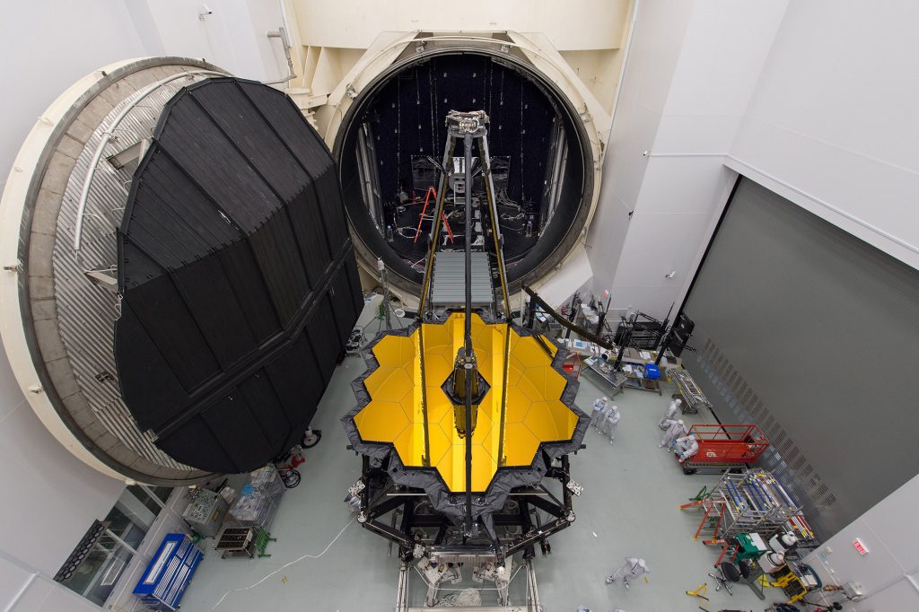 Das James-Webb-Weltraumteleskop der NASA steht vor der Tür zu Kammer A, einer riesigen thermischen Vakuumkammer im Johnson Space Center der NASA.  Das Teleskop wird in Kürze in den Raum gebracht, wo es einen heißen Sommer in Houston verbringen und bei eisigen Temperaturen getestet werden soll.  Das Teleskop wird bei der extrem niedrigen Temperatur von 50 K (-223 Grad Celsius oder -370 Grad Fahrenheit) im Weltraum betrieben, daher simuliert die NASA diese Bedingungen auf der Erde und stellt sicher, dass Optik und Instrumente nach dem Start optimal funktionieren.