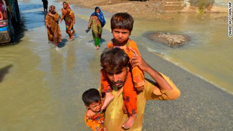 Ein Vertriebener trägt am Samstag seine Töchter aus seinem von der Flut zerstörten Haus in Jafarabad, einem Distrikt in der südwestpakistanischen Provinz Belutschistan. 