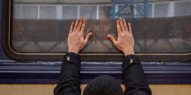Alexander, 41, drückt seine Handfläche gegen das Fenster, als er sich am Freitag, den 4. März, in einem Zug nach Lemberg am Bahnhof Kiew, Ukraine, von seiner Tochter Anna, 5, verabschiedet.  2022. Alexander muss im Krieg zurückbleiben, während seine Familie das Land verlässt, um in einem Nachbarland Asyl zu suchen.