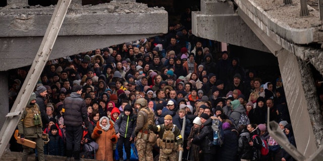 Ukrainer drängen sich unter einer zerstörten Brücke, als sie versuchen, über den Fluss Irbin in den Außenbezirken von Kiew, Ukraine, am Samstag, dem 5. März 2022, zu fliehen.