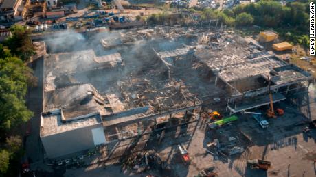 Feuerwehrleute beseitigen Trümmer in einem Einkaufszentrum in Kremenchug, Ukraine, das nach einem Raketenangriff niedergebrannt war.