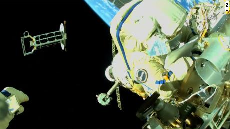 Cristoforetti arbeitet am Äußeren der Internationalen Raumstation, während Artemyev, dessen Hand unten links zu sehen ist, einen Nanosatelliten in die Umlaufbahn wirft. 