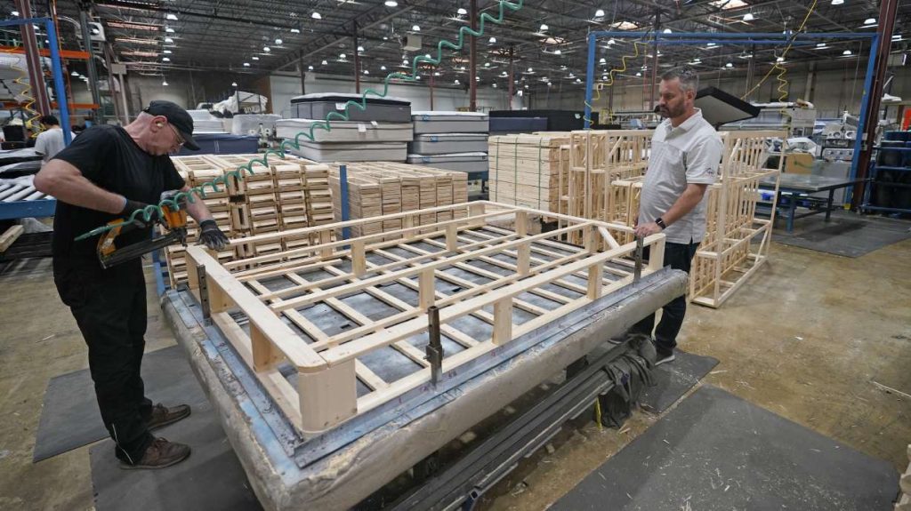 Mattress maker Schuyler Northstrom, right, of Uinta Mattress, looks on during production in his warehouse Friday, in Salt Lake City.  Inflation and rising costs for everything from labor to raw materials have forced many small businesses to raise prices. Northstrom saw a drop in customer demand after raising prices.