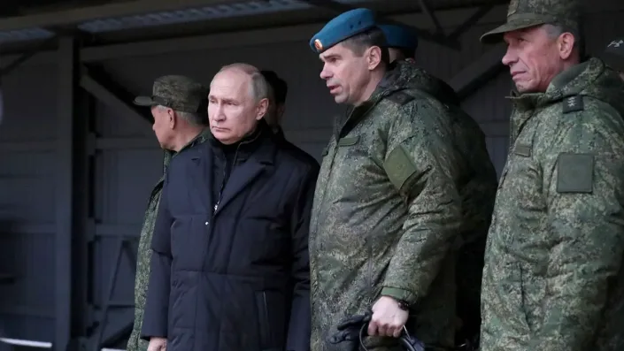 Putin steht neben einem Soldaten unter einem überdachten Bereich