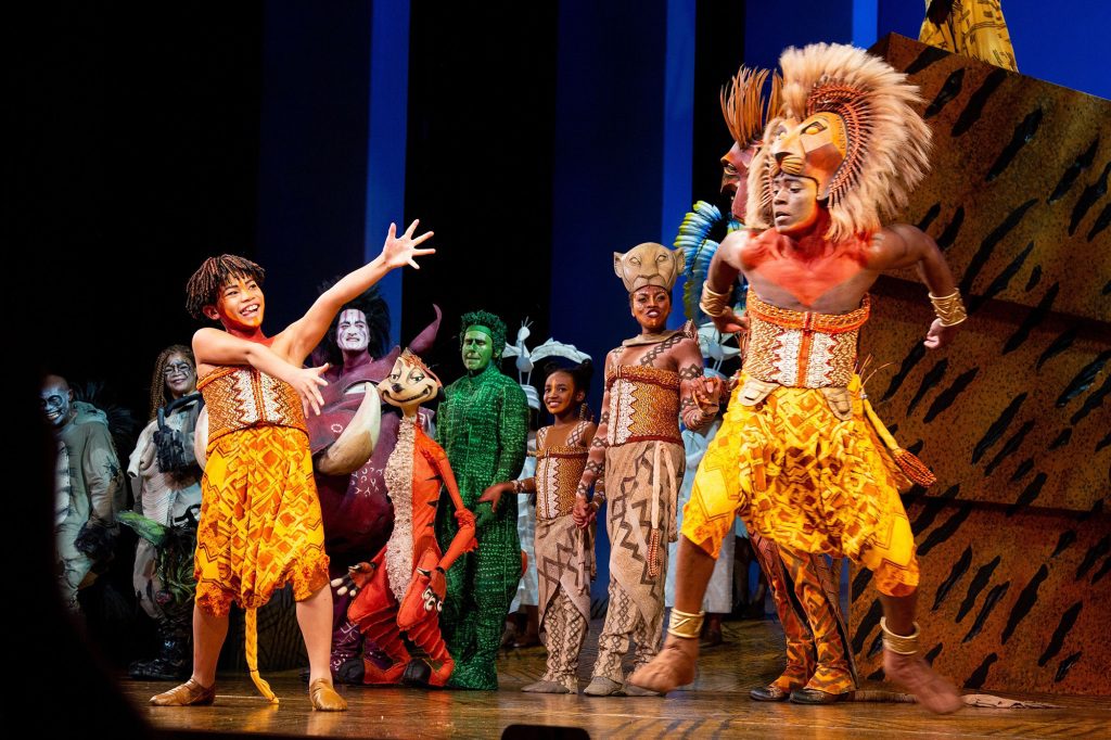 Foto von Leuten, die den König der Löwen am Broadway aufführen.